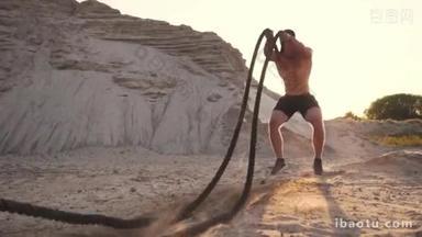 男运动员在海滩上俯卧撑, 用绳子<strong>击打</strong>地面, 在沙滩上的阳光下循环训练.